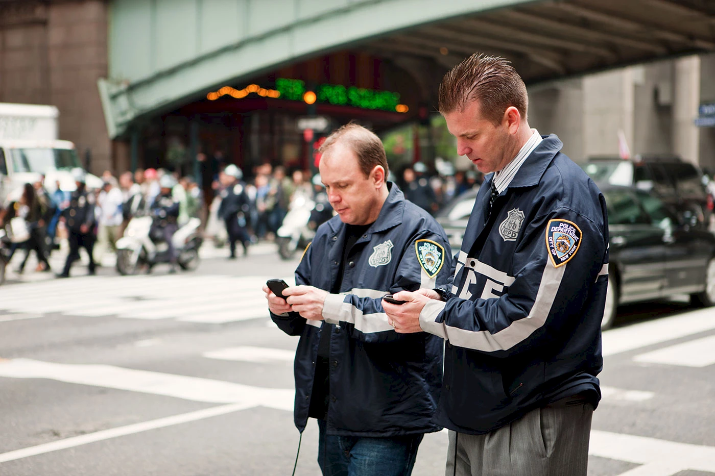 Two policemen on 42nd street using their mobile phone.