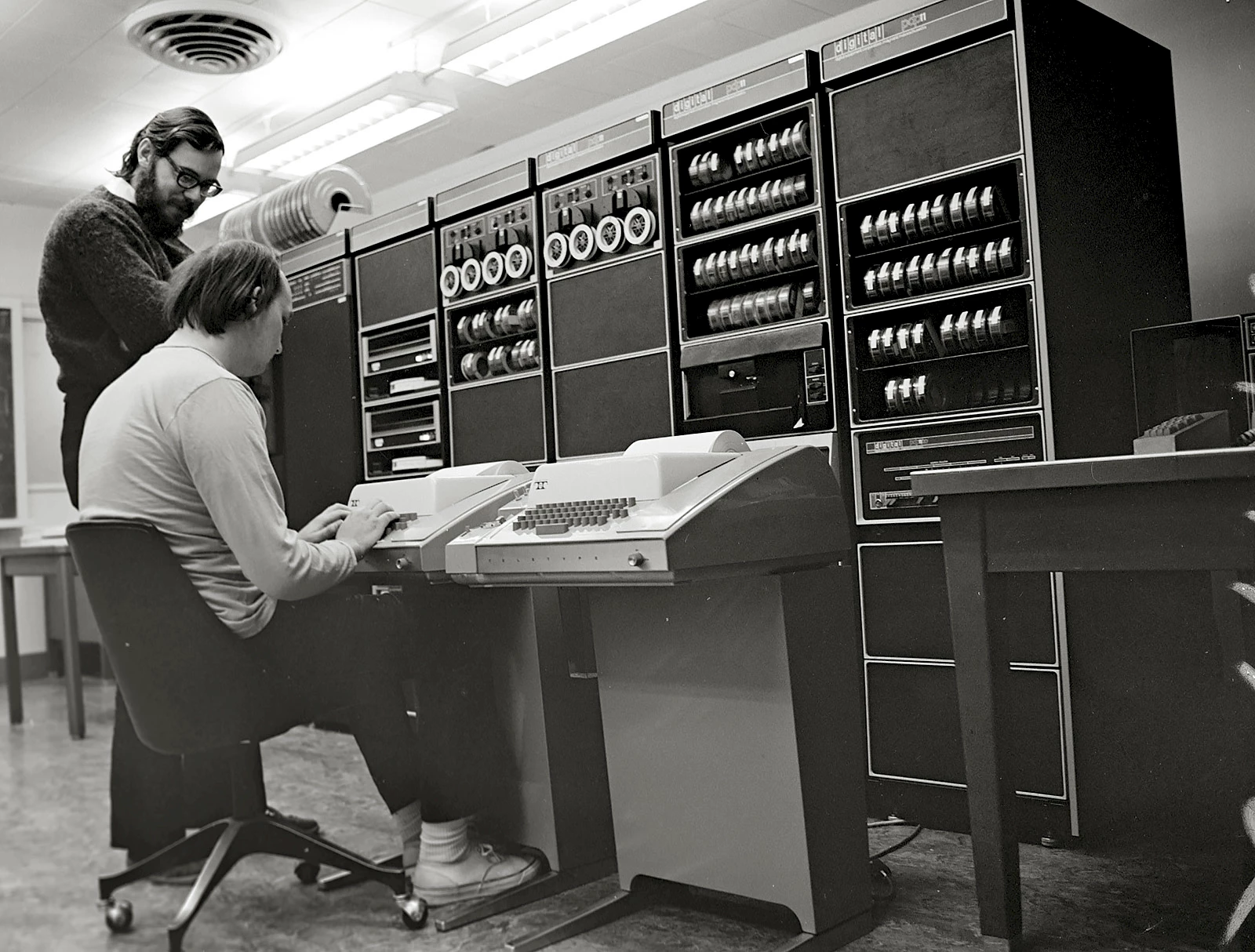 Ken Thompson (sitting) and Dennis Ritchie (standing) in front of a PDP-11.
